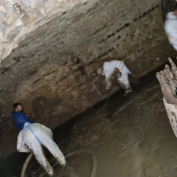 Helfer in Schutzanzügen räumen Schlamm aus einem Gewölbekeller im Ahrtal